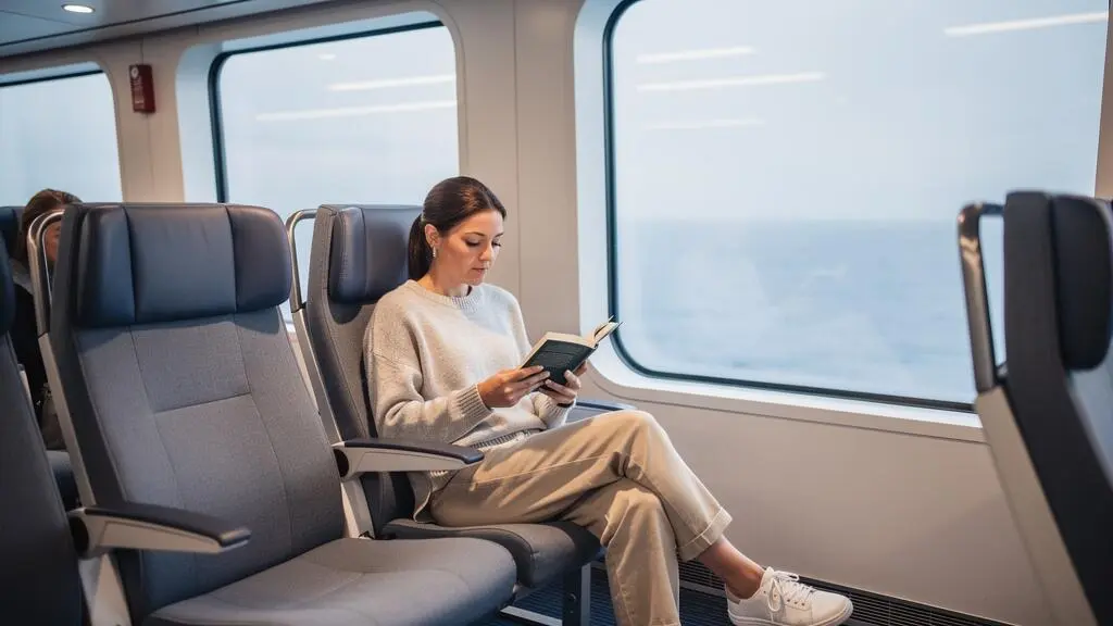 Frau liest ein Buch in einem komfortablen Passagierbereich einer Fähre während der Mittelmeerüberfahrt